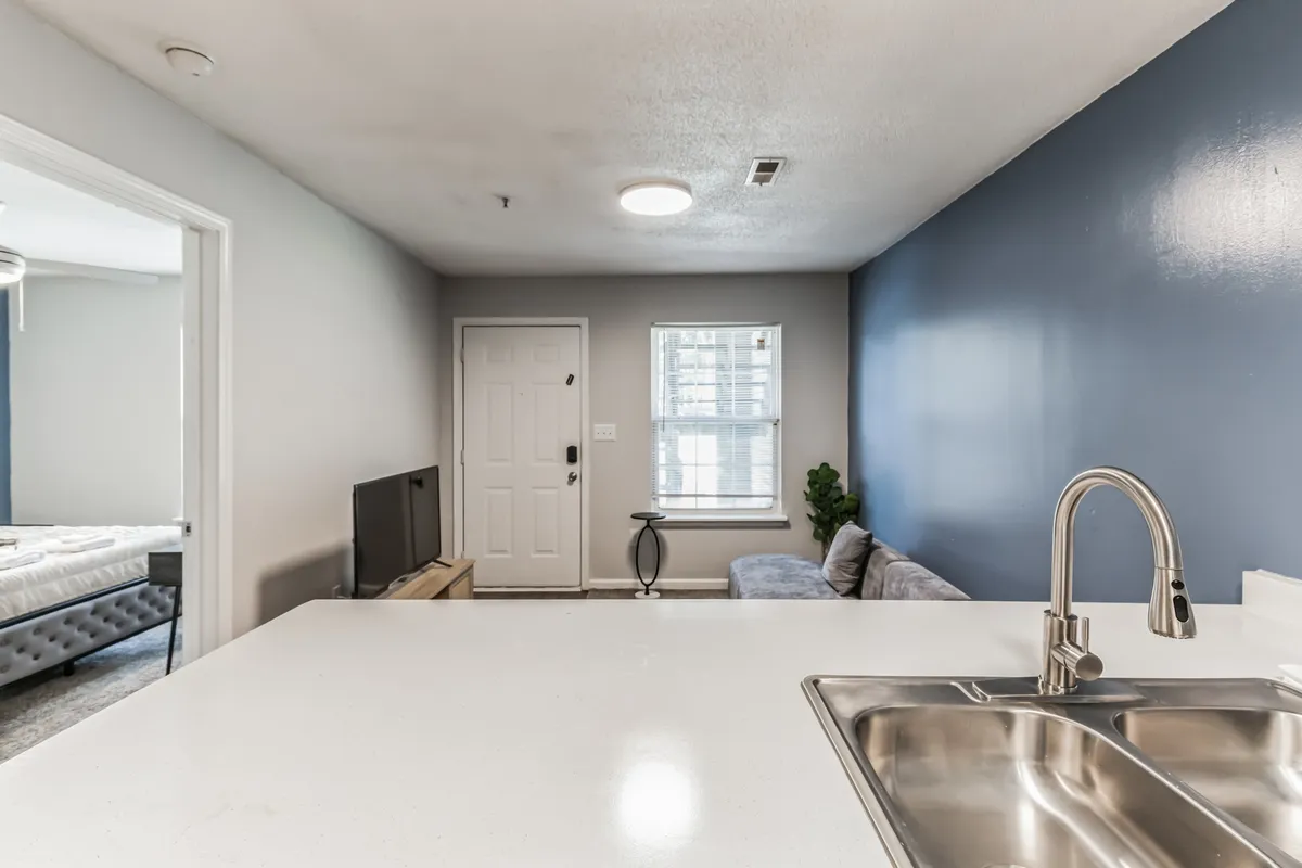 The image captures a bright and comfortable interior, highlighting the kitchen island, a plush couch, and large windows letting in natural light. Activities in this space include cooking together, enjoying the morning sun, and relaxing after a busy day.