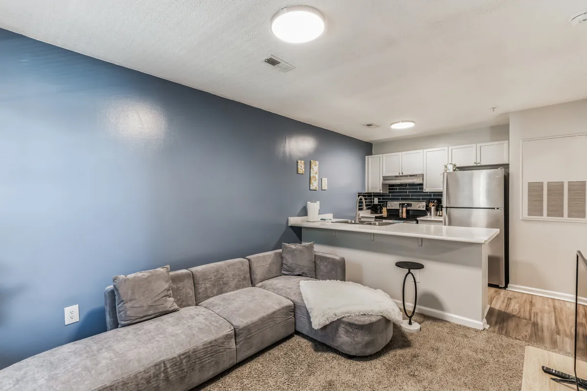 This image showcases a cozy living area featuring a comfortable sofa, kitchen counter, and stylish decorative wall art. The scene hints at social activities like relaxing, entertaining guests, or even hosting a game night, reflecting a warm and inviting atmosphere perfect for unwinding and connection.